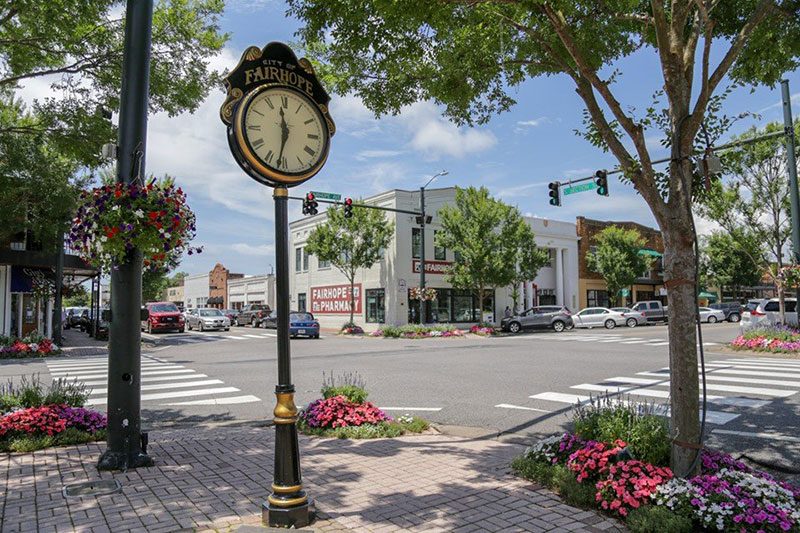 A street clock and flower beds at a downtown Fairhope intersection