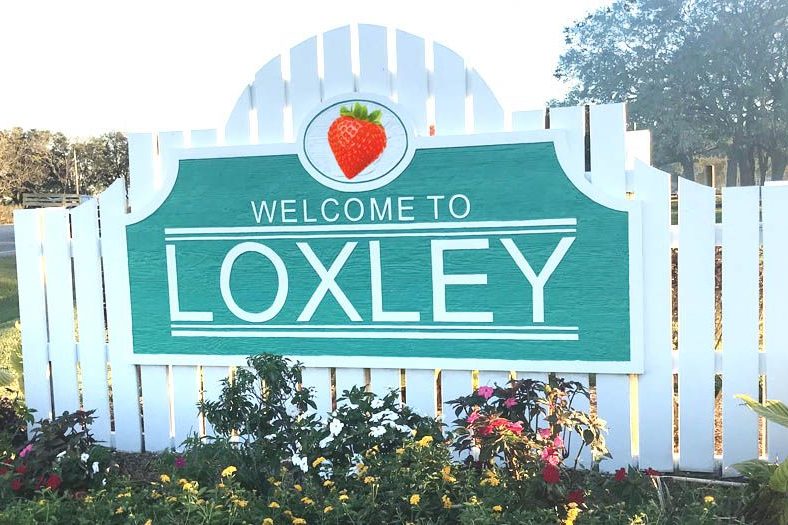 The Welcome to Loxley sign with a strawberry emblem